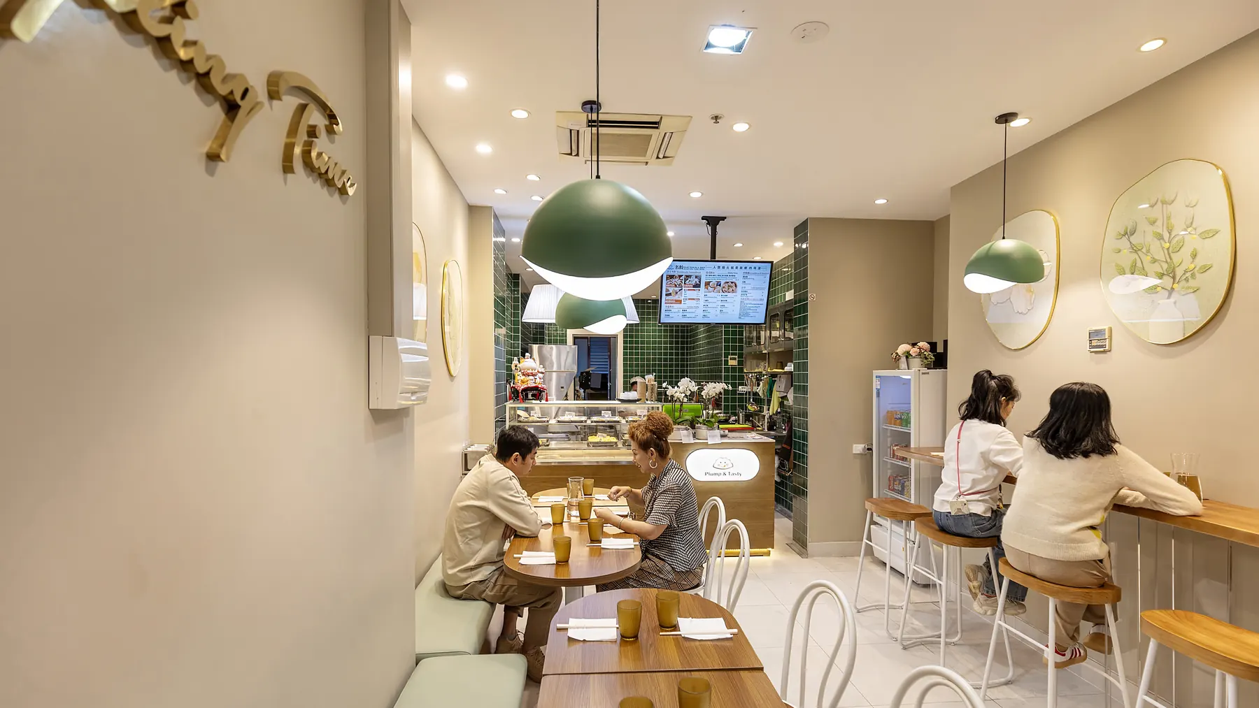 Warm interior of Dumpling Time Block Place with green pendant lights and diners