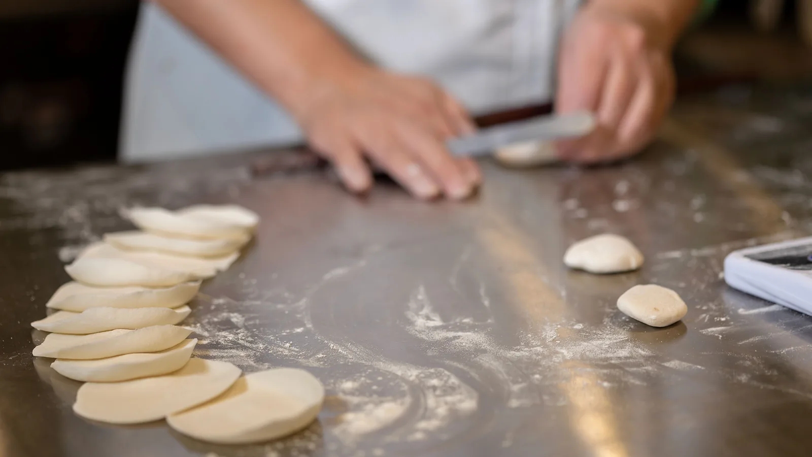 Hands rolling fresh dumpling wrappers at Dumpling Time Block Place